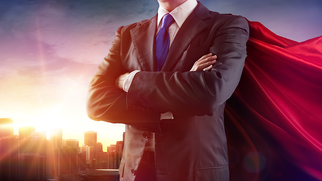 Photo of man in suit wearomg a red superhero cape
